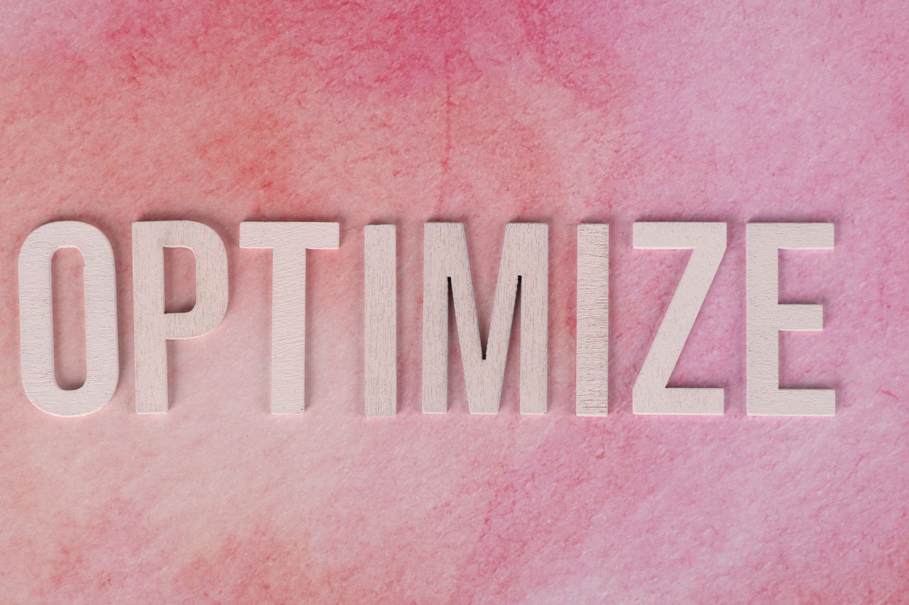 services-04 Creative display of the word OPTIMIZE on a pink textured surface.