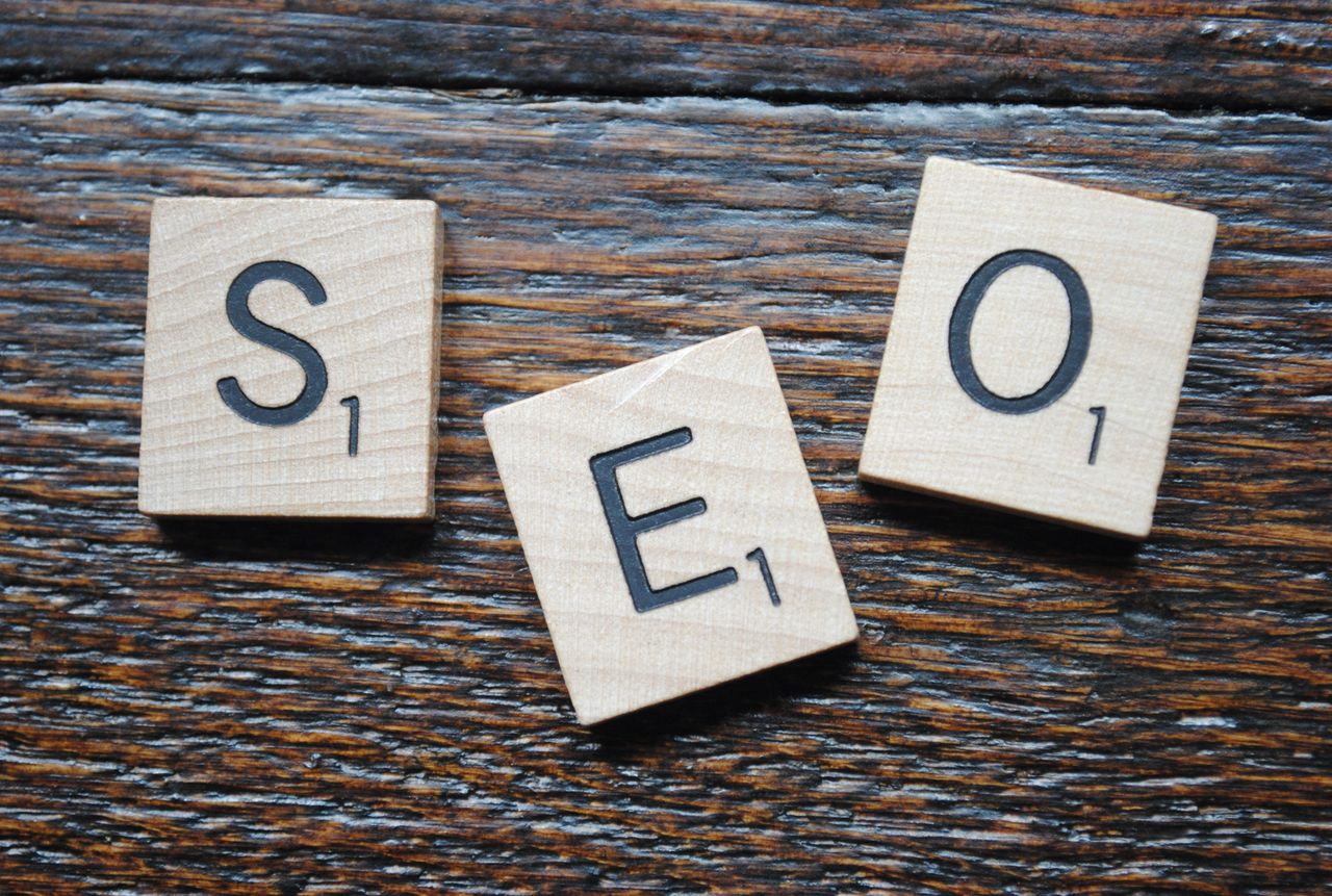 heros-img Close-up of Scrabble tiles spelling SEO on a wooden table for content strategy.