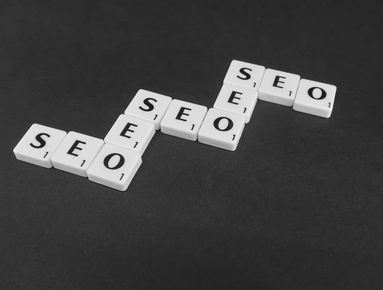 about-us-01 SEO spelled with Scrabble tiles on a black surface, representing search engine optimization concepts.